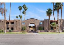 Property exterior with stone facade, lush landscaping, and stately palm trees against a clear blue sky at 7110 E Continental Dr # 2008, Scottsdale, AZ 85257