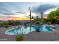 Inviting pool area featuring desert landscaping and a small waterfall under a beautiful colorful dusk sky at 10875 E Mirasol Cir, Scottsdale, AZ 85255