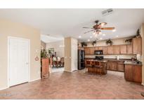 Spacious kitchen featuring wood cabinetry, black appliances, island with seating, and unique tile flooring at 22022 W Moonlight Path, Buckeye, AZ 85326