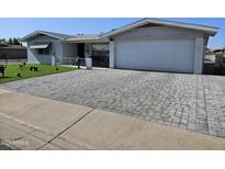 Charming home featuring well-maintained landscaping, a brick driveway, and a two-car garage at 5122 E Emerald Cir, Mesa, AZ 85206