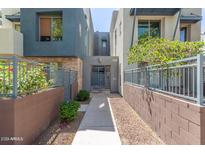 Inviting walkway leading to a gated front entrance surrounded by green landscaping and modern architecture at 615 E Portland St # 261, Phoenix, AZ 85004