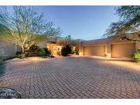 Beautiful home featuring a spacious front driveway, three-car garage, and desert landscaping, creating a welcoming ambiance at 10822 E Prospect Point Dr, Scottsdale, AZ 85262