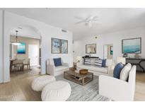 Bright living room featuring white walls, neutral furniture, and serene coastal-themed artwork at 11775 E Becker Ln, Scottsdale, AZ 85259