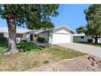 Charming single-story home with a well-maintained lawn, mature trees, and a two-car garage at 12726 W Copperstone Dr, Sun City West, AZ 85375