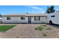 Charming single-story home with a brick walkway and gravel landscaping, complemented by a vibrant blue sky at 15049 N 25Th Pl, Phoenix, AZ 85032