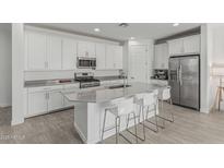 Stylish kitchen featuring white cabinets, stainless steel appliances, and a large center island with bar seating at 23068 E Stacey Rd, Queen Creek, AZ 85142