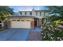 Charming front exterior featuring a stone-accented two-car garage, manicured landscaping, and welcoming front door at 29740 N 121St Ave, Peoria, AZ 85383
