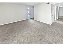 Spacious, carpeted living room with neutral walls and ample natural light coming from the front door at 3810 N Maryvale Pkwy # 1070, Phoenix, AZ 85031