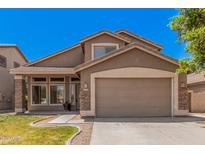 Charming two-story home featuring stone accents, a two-car garage, and a well-maintained lawn at 8037 W Mohave St, Phoenix, AZ 85043