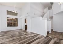 Open-concept living room with tall ceilings, wood-look floors, and stairs leading to the second floor at 8037 W Mohave St, Phoenix, AZ 85043