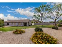Landscaped backyard with gravel ground cover, flowering bushes, a mountain view, and a covered patio for relaxing at 1043 N 90Th Cir, Mesa, AZ 85207