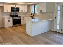 Well-lit kitchen with stainless steel appliances, white cabinets and countertops, and wood-look floors at 1301 N 44Th St, Phoenix, AZ 85008