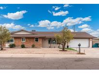 Charming single-story home featuring a brick facade, manicured landscaping, and an attached two car garage at 1985 W Anderson Ave, Phoenix, AZ 85023