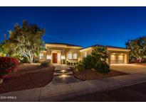 Inviting single-story home with manicured landscaping and illuminated walkway leading to a red front door at 22208 N San Ramon Dr, Sun City West, AZ 85375