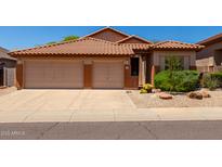 Inviting single-story home boasting a desert landscaped front yard, a terracotta tile roof, and a convenient three-car garage at 22232 N 48Th St, Phoenix, AZ 85054