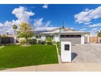 Charming home featuring a well-maintained lawn, white brick accents, solar panels and a basketball hoop above the driveway at 11025 N 45Th Ln, Glendale, AZ 85304