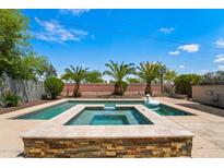 Backyard oasis featuring a sparkling pool, spa, and lush landscaping, perfect for relaxing and entertaining at 14916 W Georgia Dr, Surprise, AZ 85379