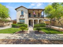 Inviting two-story home featuring a charming balcony, manicured lawn, and traditional architectural details at 21104 W Sage Hill Rd, Buckeye, AZ 85396
