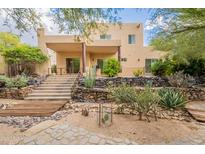 This two-story home boasts a covered patio, stone stairs, desert landscaping, and a view of the natural terrain at 39017 N Habitat Cir, Cave Creek, AZ 85331