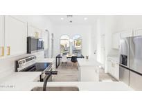 Bright modern kitchen featuring white cabinets, quartz countertops, stainless steel appliances, and an adjacent dining area at 7838 N 110 Ln, Glendale, AZ 85307