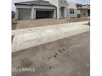 New construction house with a three-car garage and brick paver driveway at 14800 W Lariat Ln, Surprise, AZ 85387