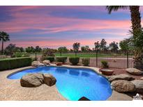 A beautiful backyard pool with rock features and a view of the golf course at sunset at 22504 N San Ramon Dr, Sun City West, AZ 85375