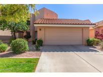 Charming home featuring a two-car garage, a lovely tiled roof, and attractive landscaping with gravel and manicured shrubs at 6459 E Sugarloaf St, Mesa, AZ 85215
