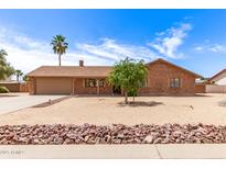 Charming single-story brick home with a two-car garage, desert landscaping, and a palm tree in the front yard at 8913 W Country Club Trl, Peoria, AZ 85383