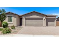 Tan home featuring a two-car garage, beautiful landscaping, and a brick driveway at 1268 E Jahns Dr, Casa Grande, AZ 85122