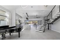 Bright and spacious living room with modern staircase, piano, and kitchen view at 20274 N 76Th Way, Scottsdale, AZ 85255