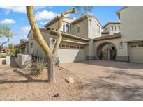 Inviting home exterior featuring desert landscaping, a two-car garage, and an arched entryway with gated access at 20802 N Grayhawk Dr # 1123, Scottsdale, AZ 85255