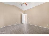 Neutral bedroom showcasing vaulted ceiling, light-tone walls, light tile flooring, and a white paneled door at 22576 N Davis Way, Maricopa, AZ 85138