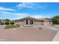 Inviting home boasts a well-manicured lawn, mature plants, and desert landscaping at 22576 N Davis Way, Maricopa, AZ 85138
