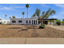 Charming white stucco home featuring unique architecture and desert landscaping with palm trees at 6401 E Voltaire Ave, Scottsdale, AZ 85254