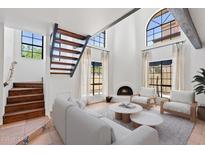 Bright living room with a fireplace, large windows, staircase, and comfortable seating area at 8844 S 51St St # 3, Phoenix, AZ 85044