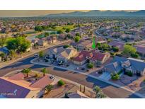 Stunning aerial view of homes in a golf course community with mountain views in the distance at 19472 N Marble Canyon Ct, Surprise, AZ 85374
