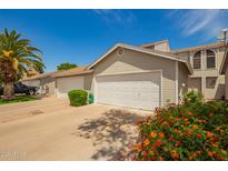 A well maintained townhome garage featuring a white door, adjacent to a blooming flower bed and palm tree at 3134 E Mckellips Rd # 139, Mesa, AZ 85213
