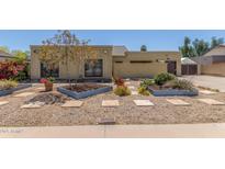 Inviting single-story home featuring xeriscape landscaping, mature trees, and stone walkway at 4233 W Michigan Ave, Glendale, AZ 85308