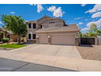 Traditional two-story home featuring a three-car garage, well-manicured lawn, and neutral color palette at 43612 W Chambers Ct, Maricopa, AZ 85138