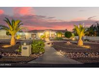 Charming home featuring desert landscaping with beautiful palm trees and a well-lit walkway at 5511 N 128Th Dr, Litchfield Park, AZ 85340
