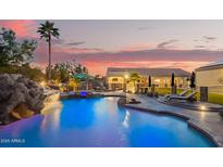 Backyard oasis with a large pool, waterfall, slide, and covered seating area at 5511 N 128Th Dr, Litchfield Park, AZ 85340