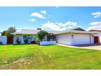 Beautiful single-story home featuring a lush green lawn, white exterior, and attached two-car garage at 5634 N 39Th Ave, Phoenix, AZ 85019