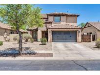 Two-story home featuring a tile roof, large driveway, and low maintenance desert landscaping at 14200 W Larkspur Dr, Surprise, AZ 85379