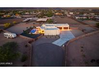 Sprawling property with a private pool, horse stables, and a long driveway at dusk at 2609 W Lavitt Ln, Phoenix, AZ 85086