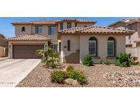 Beige two-story home with a brown roof, lush landscaping, and a two-car garage at 6870 S Crestview Dr, Gilbert, AZ 85298
