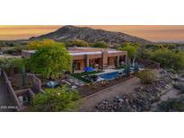 Desert home featuring a large pool, landscaping, and mountain views at sunset at 8300 E Lone Mountain Rd, Scottsdale, AZ 85266