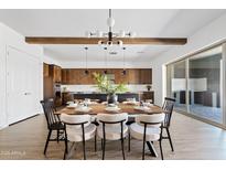 Open concept dining room with modern light fixture, wood beams, and dining table set for dinner at 10134 E Talon Ave, Mesa, AZ 85212