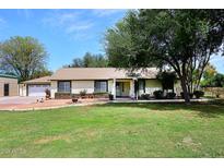 Charming single-story home with green lawn, mature trees, and neutral toned facade at 17730 E Brooks Farm Rd, Gilbert, AZ 85298