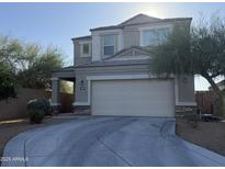 Two-story home featuring a two-car garage and a covered porch with stone accents. Landscaped with desert trees and bushes at 3402 N 300Th Dr, Buckeye, AZ 85396