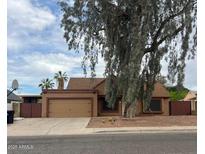 Charming single-story home with desert landscaping, a two-car garage, and a mature shade tree at 1110 E Utopia Rd, Phoenix, AZ 85024